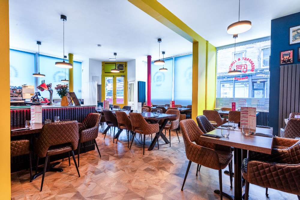 The dining room looking out to Polwarth Crescent — big shopfront windows, tan tub chairs, parquet floor