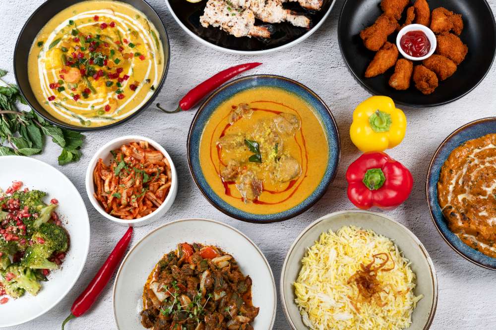 An overhead Bell Bottom spread — korma, biryani, pakora, grilled chicken, peppers and chillies